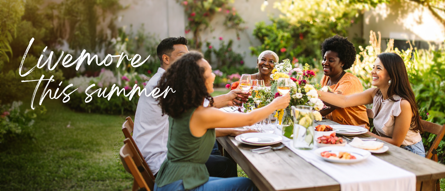 Group of friends sitting at a wooden dinner table in a backyard garden